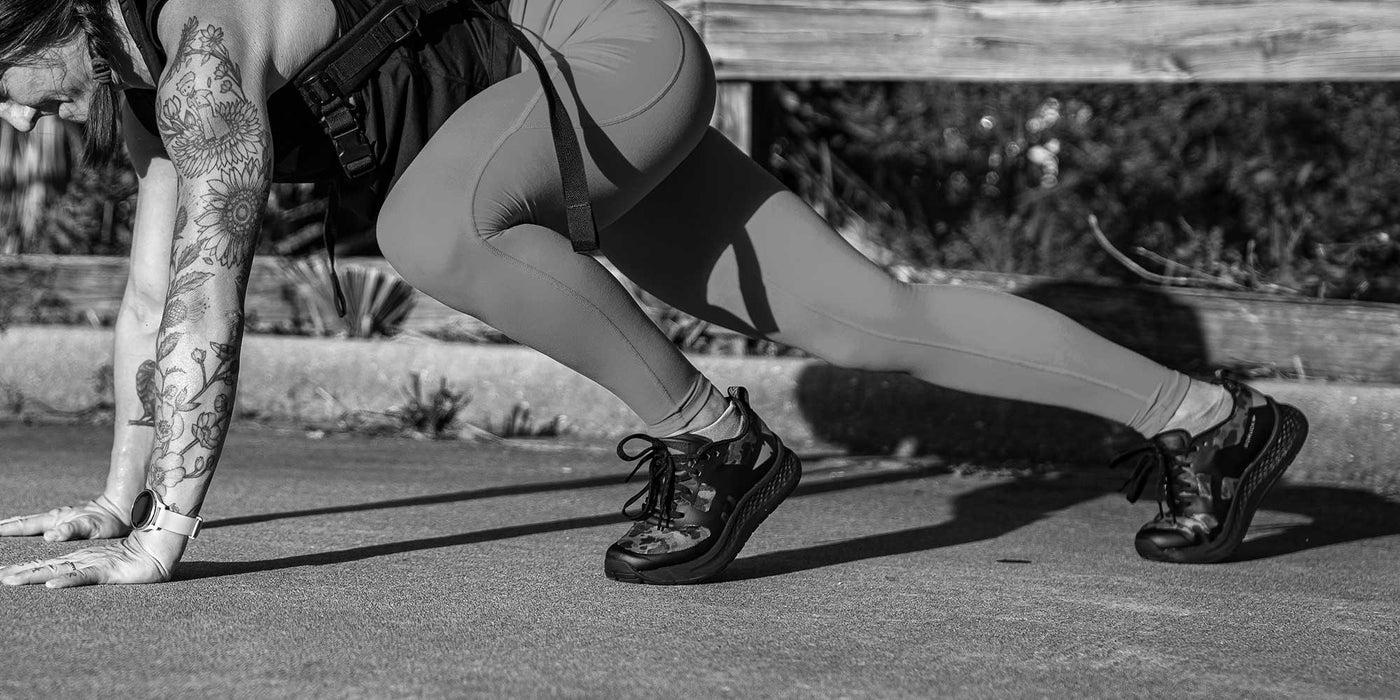 Person in athletic gear doing a crawling exercise outdoors on pavement.