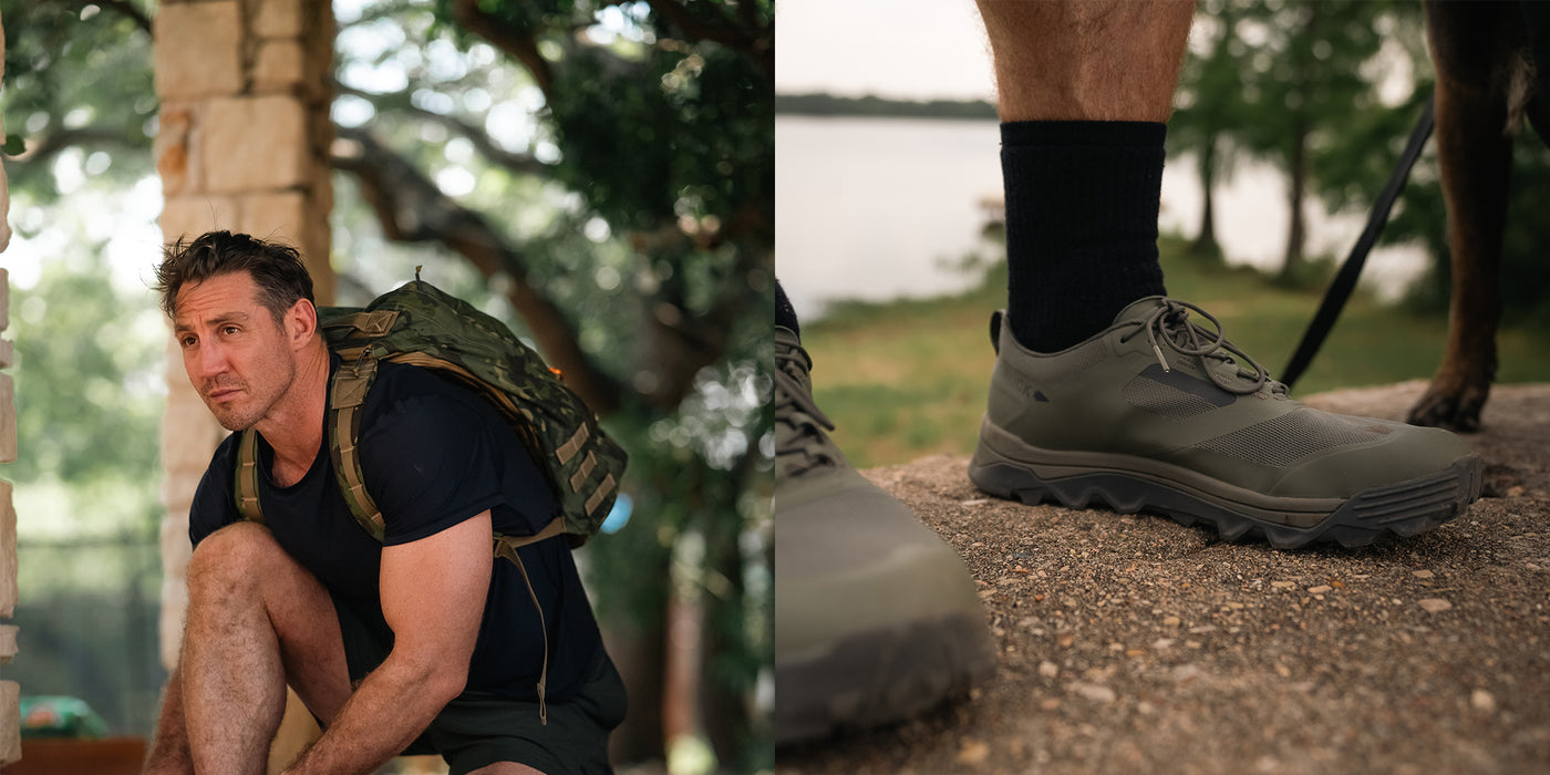 Man with backpack kneeling outdoors; close-up of legs wearing hiking shoes on a stone path near water.