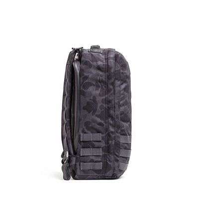 Side view of the GR1 USA - Cordura in black camouflage, crafted with Special Forces-grade materials. It features a zipper and extra strap loops, ideal for tackling the GORUCK Challenge.