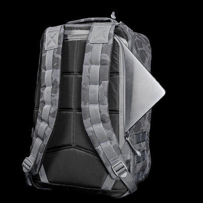 The GR1 USA - Cordura (The Original Ruck) features a gray camo design made from Special Forces-grade materials, padded straps, and a laptop visible through the zippered compartment—ideal for a GORUCK Challenge or daily adventures.