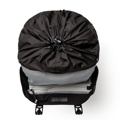 A black M23 Cordura Spearhead Shrapnel rucksack from GORUCK, with its drawstring top open, showcases neatly organized clothing and gear inside, accented by a visible mesh pouch. Made from durable materials, it embodies the practicality reminiscent of an M1945 Field Pack.