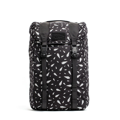 The M23 - Cordura - Spearhead Shrapnel by GORUCK is a black rucksack with a drawstring top and buckles, adorned with a pattern of small white airplane icons evenly distributed across its durable material.