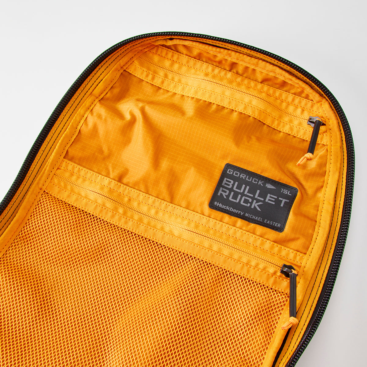 Open orange Bullet Ruck by Michael Easter, crafted from lightweight 420D ROBIC® Ripstop Nylon, featuring a mesh pocket and a "Bullet 15L" label.