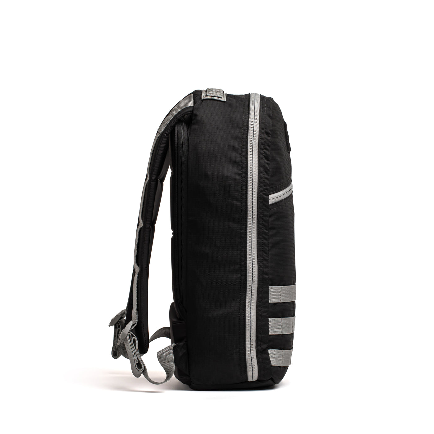 The image shows a side view of the Bullet Ruck Laptop - Ripstop ROBIC® - 16L by GORUCK in black, featuring gray zippers and accents. Its design includes a spacious main compartment, a dedicated laptop section, adjustable padded shoulder straps, and several smaller exterior pockets. The backpack is displayed against a white background.