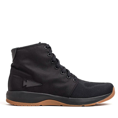 Introducing the Women's Ballistic Trainers - Mid Top by GORUCK, a high-top sneaker meticulously crafted from durable black CORDURA® Ballistic Nylon. It features black laces and a contrasting gum outsole. This fitness footwear is designed with 3X Support™ and is subtly adorned with a black reflective spearhead logo, seamlessly blending athletic style with casual comfort.