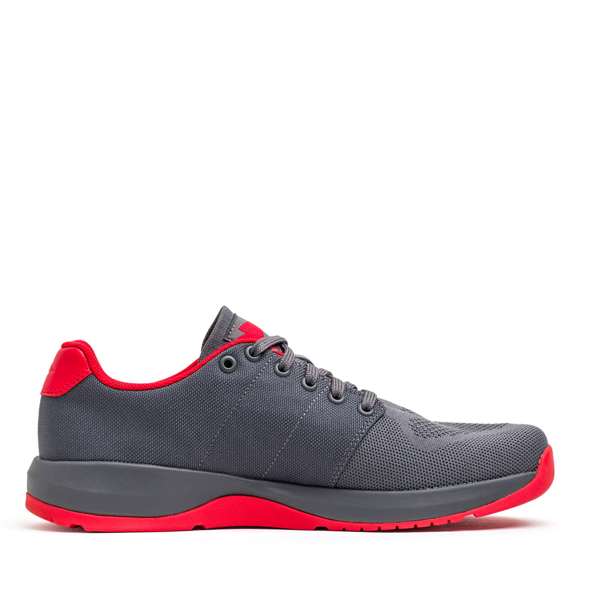 Showcasing its side profile against a white background, the GORUCK Men's Ballistic Trainers in Wolf Grey and High Risk Red feature a breathable mesh design with dark gray laces. This shoe, ideal for functional fitness enthusiasts, boasts red accents on the tongue, heel, and sole complemented by a reflective spearhead detail.