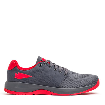 Introducing the Women's Ballistic Trainers by GORUCK in Wolf Grey with High Risk Red, featuring a red reflective spearhead detail on the side. These athletic shoes boast a red sole and interior lining, and are designed with 3X Stability technology for superior support during workouts. The textured surface of these trainers is displayed against a white background.