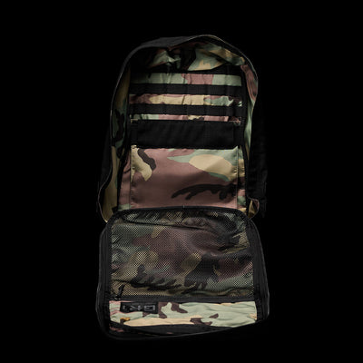 Open the GR1 Birdwell camouflage backpack from GORUCK, featuring multiple compartments and mesh pockets, expertly crafted to embody American craftsmanship. With its versatile design set against a sleek black background, this accessory is reminiscent of its durable SurfNyl™️ fabric.