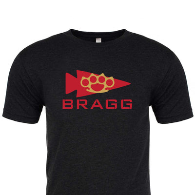 The Bragg GORUCK Challenge Tee - Tri-Blend, created by GORUCK, is a black T-shirt made from high-quality tri-blend fabric. It showcases an eye-catching red arrowhead and paw print design above the word "BRAGG." Ideal for those motivated by Special Forces training, this shirt represents more than fashion—it's a symbol of resilience.