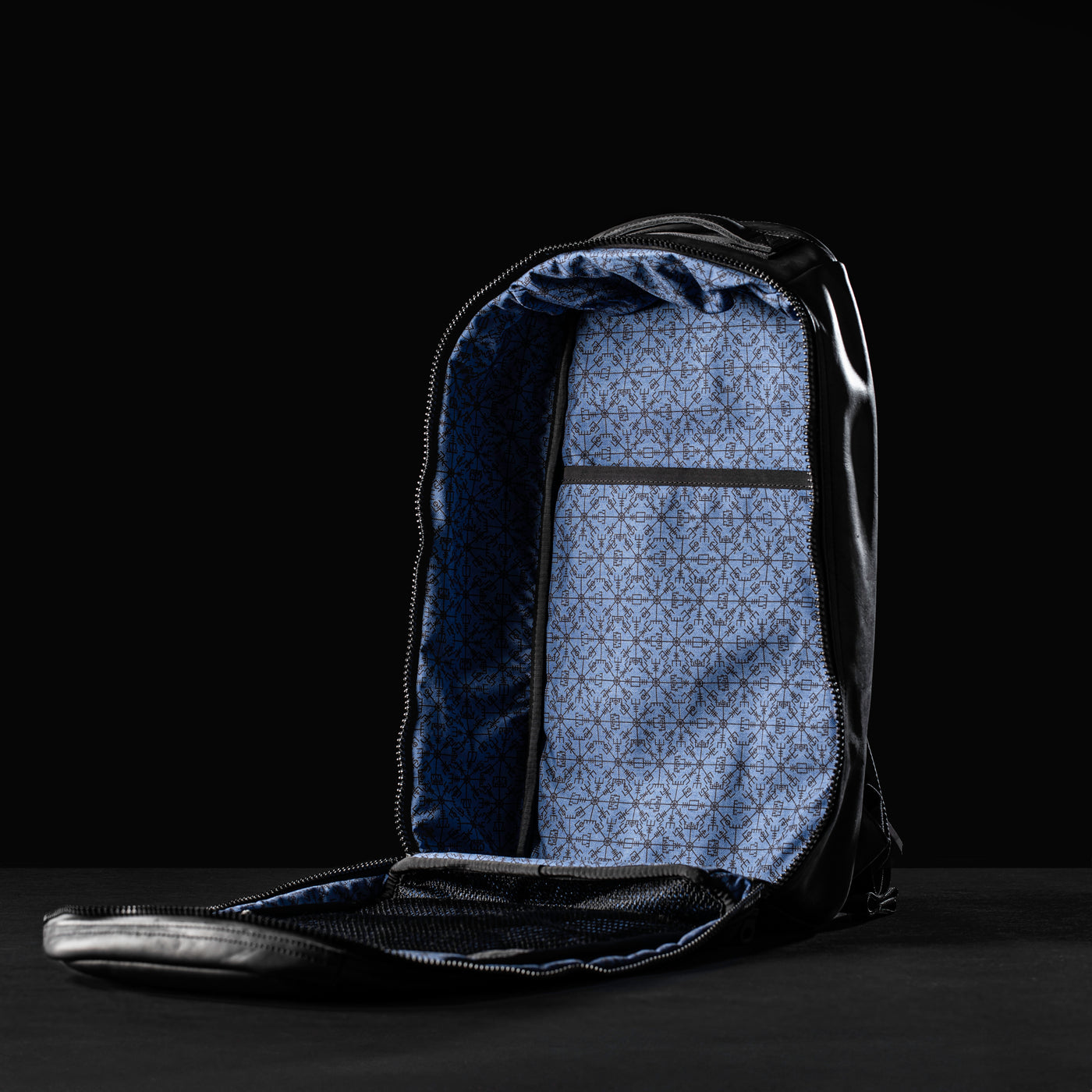 The GORUCK Bullet Ruck x Carryology - Berserker Viking backpack is open, showcasing a blue patterned interior. The lining features geometric designs that stand out against a dark background, highlighting the roomy inside and making it ideal for any modern-day berserker's adventures.