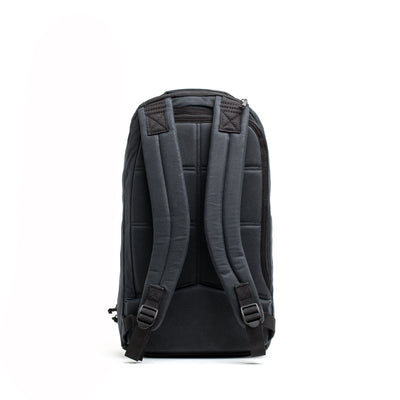 Against a plain white background, the Bullet Ruck - Waxed Canvas by GORUCK stands upright, featuring its retro charm with padded shoulder straps and a quilted back panel reminiscent of a classic design.