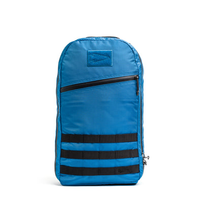 The Bullet Ruck - Ripstop ROBIC® is a blue daypack with black horizontal stripes, crafted from durable Robic nylon. It includes a front zippered pocket and extra padded straps for comfort.