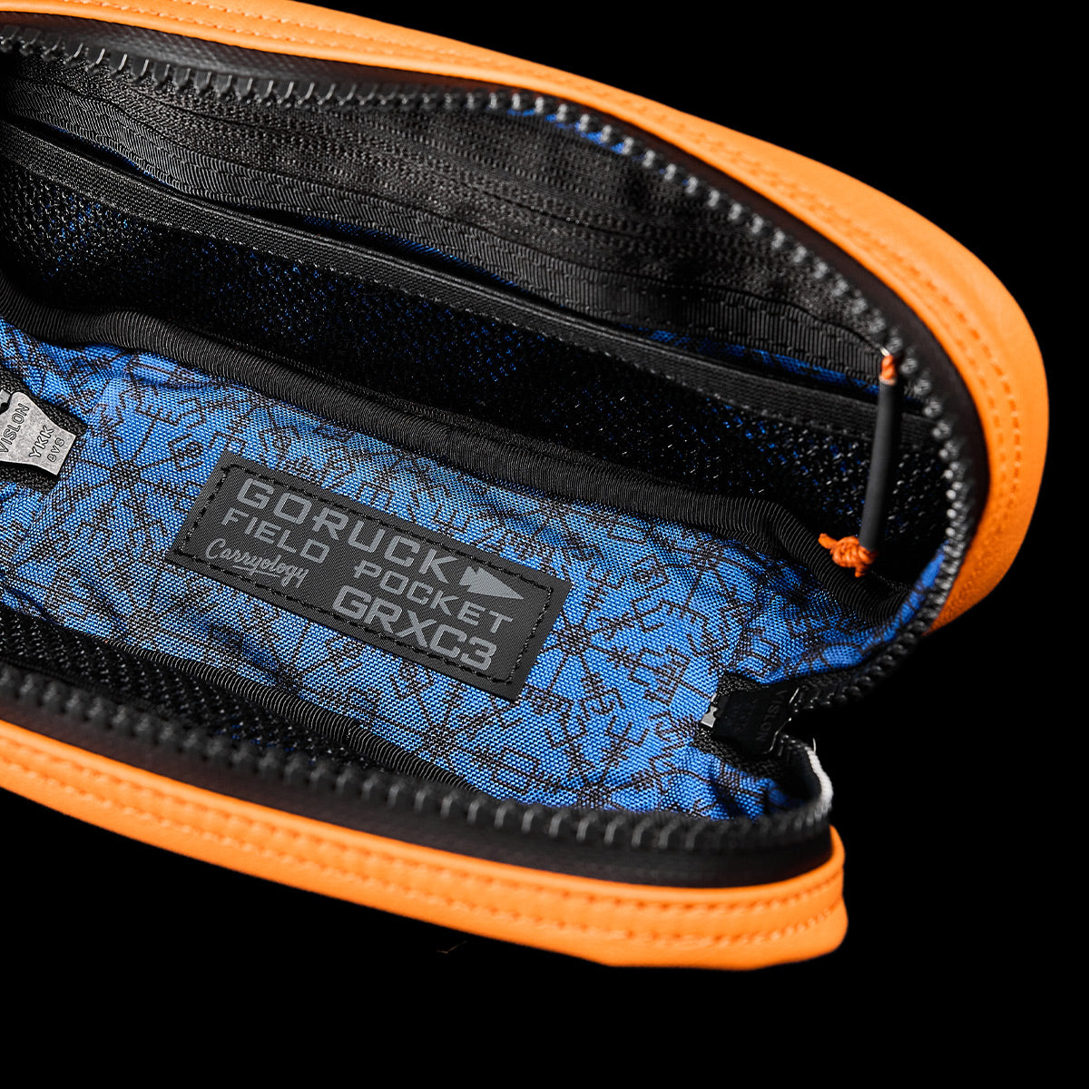 Open view of the Echo Field Pocket x Carryology - Berserker Viking, an orange pouch with a black zipper that reflects the resilience of a Viking shield. Inside, the blue lining evokes the Nordic seas and displays a label reading GORUCK. The berserker-inspired compartments exhibit organizational prowess in patterned fabric.