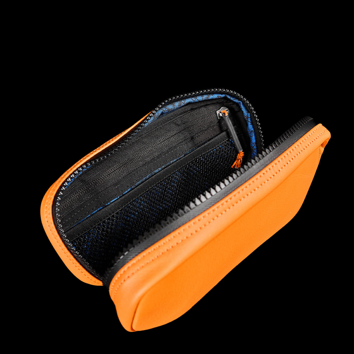 The Echo Field Pocket x Carryology - Berserker Viking by GORUCK, with its vibrant orange zippered design reminiscent of a Viking's travel gear, opens to showcase inner compartments lined in black and blue. One section is highlighted by a small zipper pull that contrasts strikingly against the solid black backdrop.