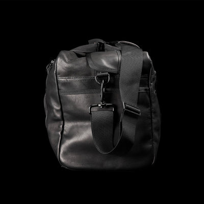 The Kit Bag x Carryology - Berserker Viking by GORUCK, a black leather duffel bag set against a dark backdrop, evokes the essence of a Viking kit bag. It comes with a durable shoulder strap and two zippered compartments, showcasing its rugged and practical design ideal for contemporary Norsemen warriors.