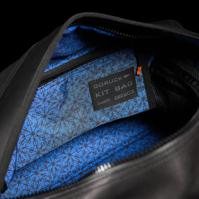 Close-up of an open black Kit Bag x Carryology - Berserker Viking by GORUCK, reminiscent of a Viking kit bag, showcasing its blue patterned interior. A label reads GORUCK KIT BAG GRX-C3 with additional small text beneath it. The bag boasts a spacious compartment fit for modern-day Norsemen warriors.