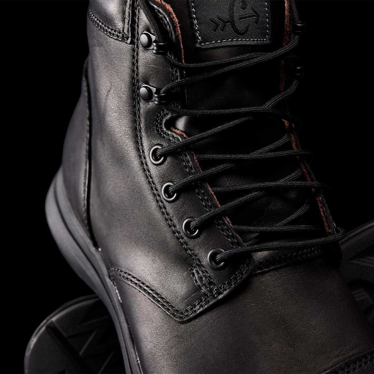 Close-up of the limited edition MACV-1 Traveler x Carryology - Berserker Viking boot by GORUCK, showcasing its black leather construction with detailed stitching and sturdy lacing. This travel boot features metal eyelets and a rugged sole, crafted from water-resistant leather, all set against a dark background.