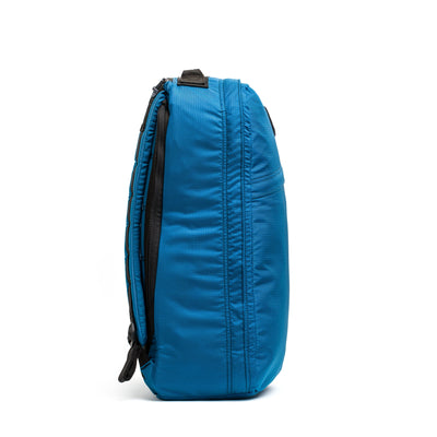 Side view of the GR1 USA - Ripstop ROBIC® by GORUCK: an ultra lightweight blue backpack made from water-resistant 420D Robic Ripstop Nylon, showcasing a sleek design with zippers and a carrying handle on a white background.