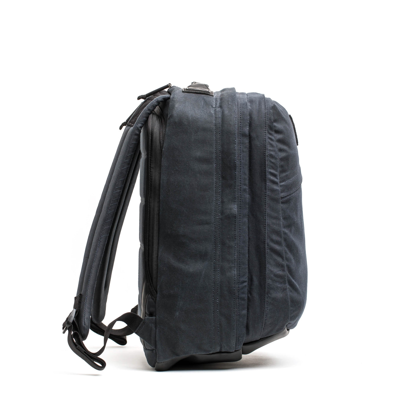 A side-angle view of the dark gray GORUCK GR2 - Waxed Canvas rucksack, crafted from waxed duck canvas. It boasts multiple compartments, a sturdy handle, and adjustable shoulder straps. Its durable material makes it perfect for travel or daily use, set against a plain white background.