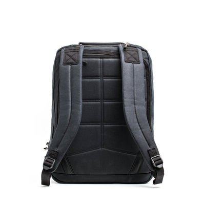 A sleek, black GR2 - Waxed Canvas rucksack from GORUCK is shown from the back, showcasing its padded shoulder straps and quilted back panel. The backpack features a simple, modern design with black accents and appears to offer ample storage space.