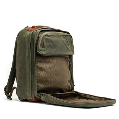 The GR2 - Waxed Canvas by GORUCK is crafted from durable waxed duck canvas and has a zippered front compartment that opens wide to reveal an internal mesh pocket. Equipped with two comfortable shoulder straps and accented with Red Wing Leather, this green travel backpack seamlessly combines style with functionality.