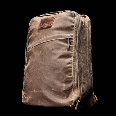 A well-traveled, sand-dusted rucksack featuring a noticeable GORUCK brand patch and zippers, captured against a dark background. The texture of the GR1 USA - Heritage backpack hints at its journey through dusty terrain.