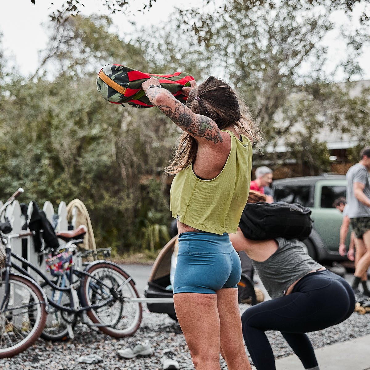 Women exercising outdoors with fitness equipment and parked bicycles nearby demonstrate the versatility of Women’s Squat Shorts - ToughFlex for ultimate comfort and flexibility during movements.