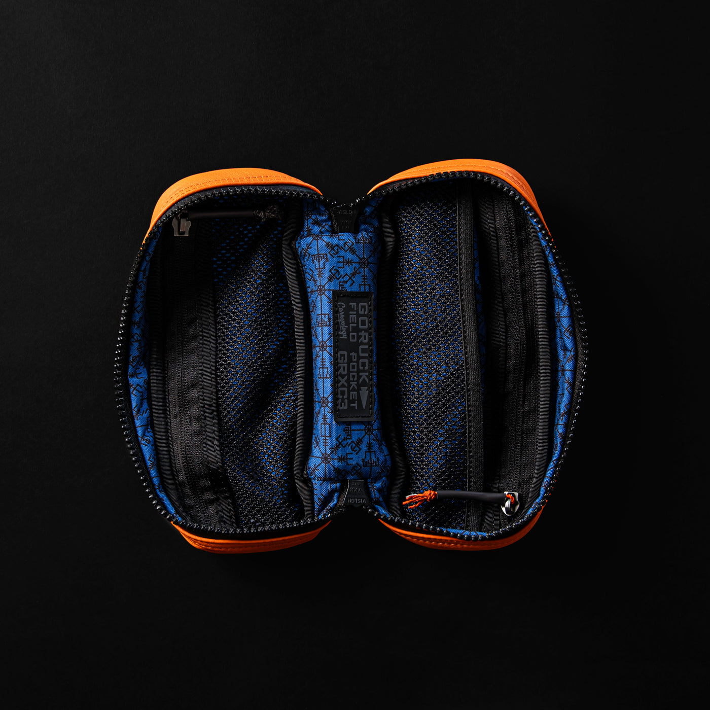 The Echo Field Pocket x Carryology - Berserker Viking by GORUCK is an open zippered pouch adorned with orange edges and a blue interior showcasing black Viking-inspired patterns. Inside, it boasts two main mesh compartments alongside a central fabric label with inscriptions. Set against a striking black background, it's designed to resonate with the spirit of Norsemen.