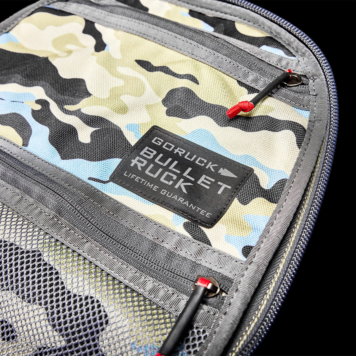 Streamlined camo backpack equipped with zippers and padded straps, featuring a patch that reads "GORUCK Bullet Ruck Classic - Cordura, Lifetime Guarantee." Perfect for adventurers in need of a durable daypack.