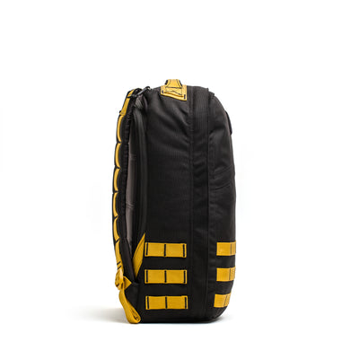 The side view of a black GR1 USA - Cordura rucksack by GORUCK, featuring yellow straps and accents, highlights its Special Forces grade durability against a pristine white background.