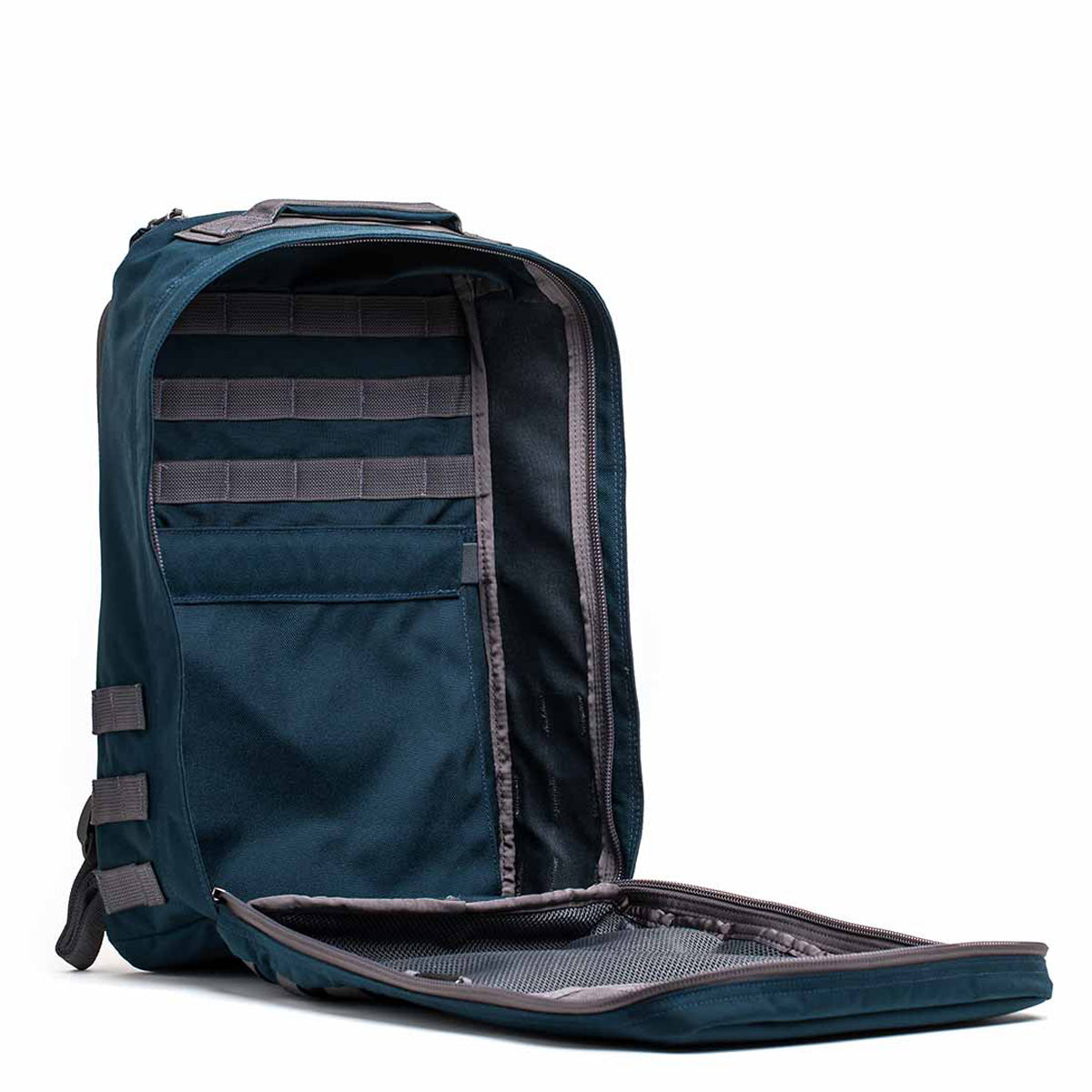 The GR1 USA - Cordura, a dark teal backpack built with Special Forces grade materials and a gray interior, boasts multiple compartments. Its design is reminiscent of the GORUCK Challenge and it's shown against a white background.