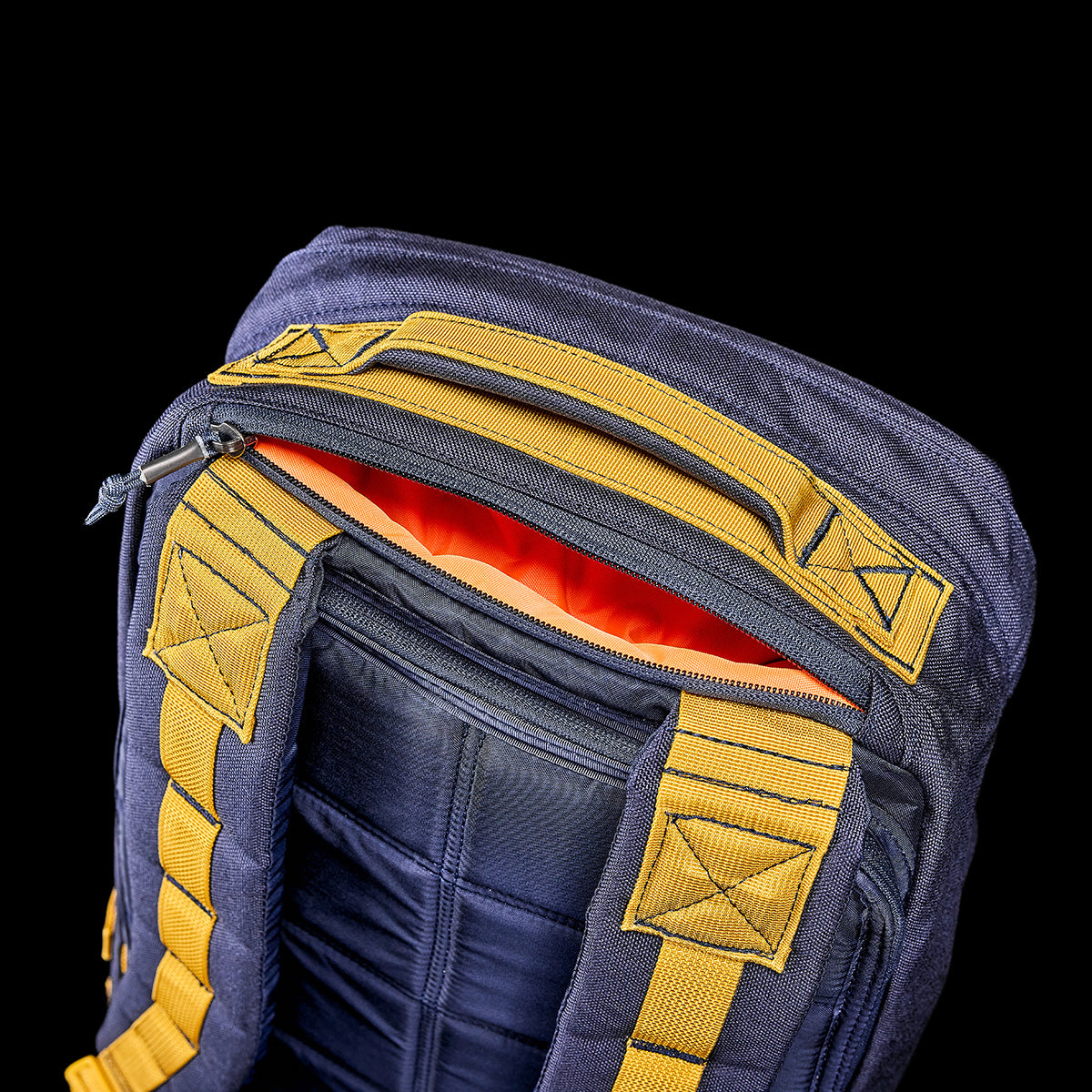 A GR1 USA - Cordura rucksack from GORUCK, featuring a blue and yellow design, stands against a black background. Its open top reveals an orange interior along with a bombproof laptop compartment crafted to Special Forces grade standards.