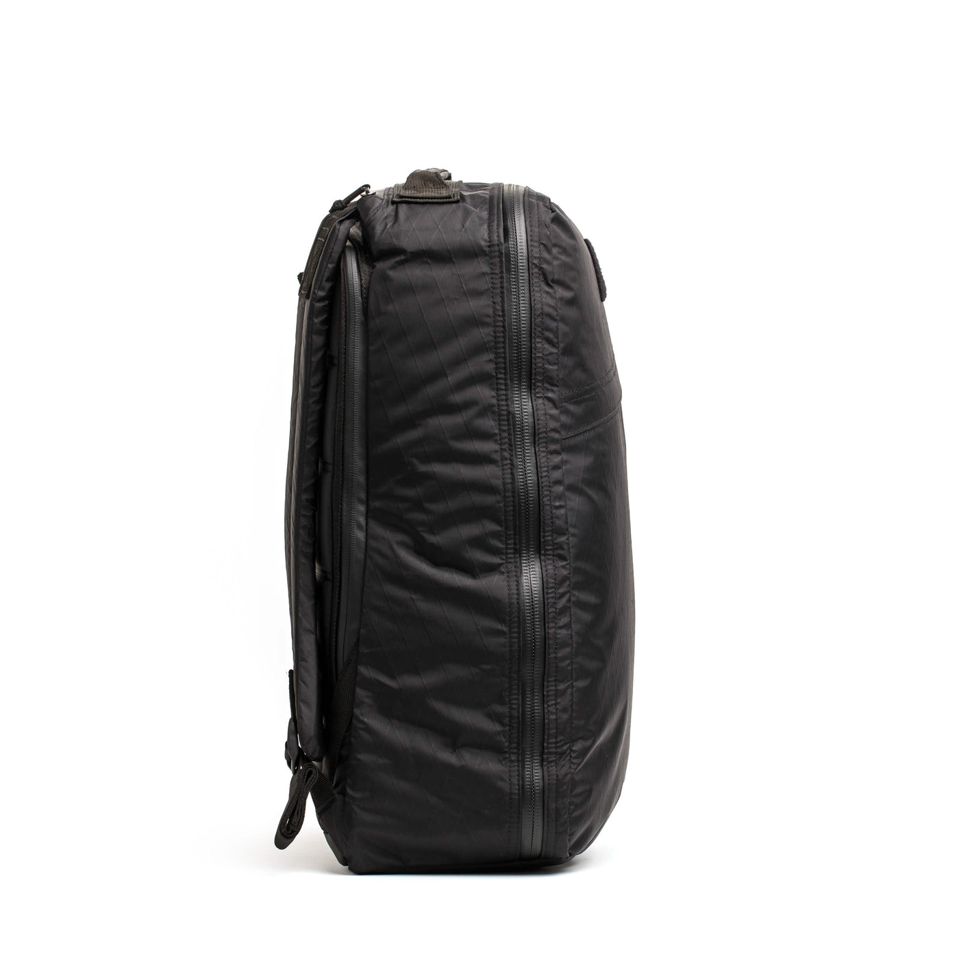 Side view of a sleek black GR1 USA - X-PAC backpack by GORUCK, featuring multiple zippers and a smooth, waterproof fabric. The backpack appears compact and durable, making it perfect for travel or daily use.