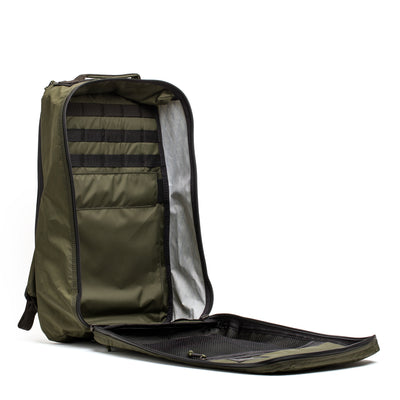 The GORUCK GR1 USA - X-PAC rucksack in olive green boasts numerous compartments and zippers, combining both durability and style. Its waterproof design makes it ideal for adventurous journeys, standing out elegantly against a white background.