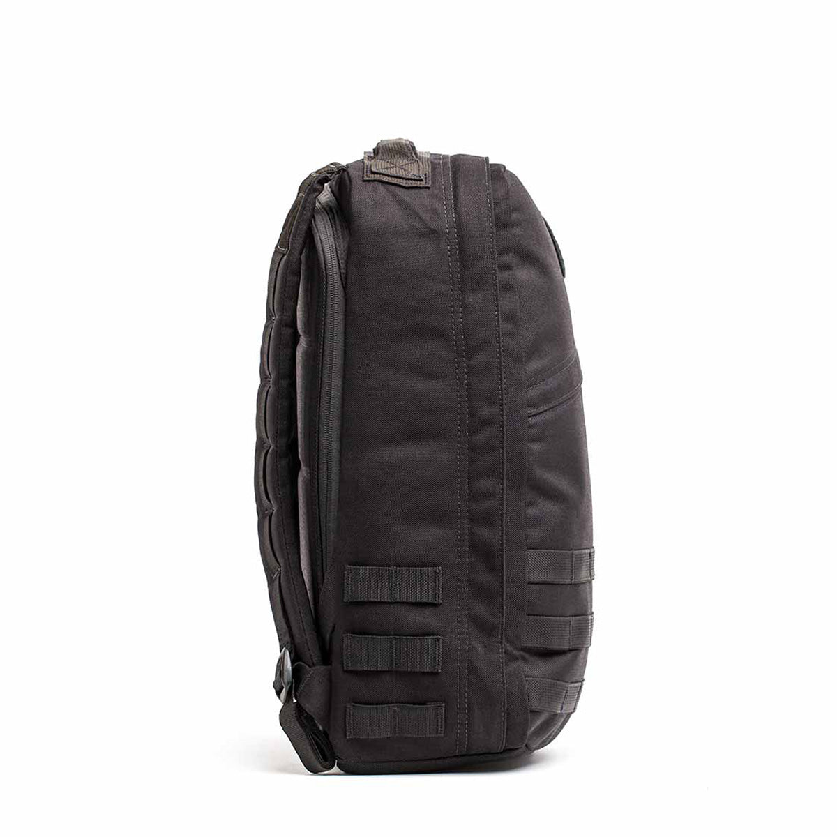 Side view of the GR1 USA Throwback, a black tactical backpack made of durable 1680 Ballistic Nylon, featuring multiple compartments, adjustable straps, and a bombproof laptop compartment for ultimate protection.