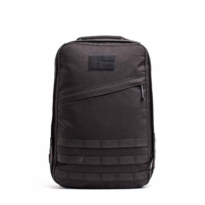 The GR1 USA Throwback is a black tactical backpack made from durable 1680 ballistic nylon, featuring a bombproof laptop compartment, front zipper pocket, horizontal strap details, and a top handle.