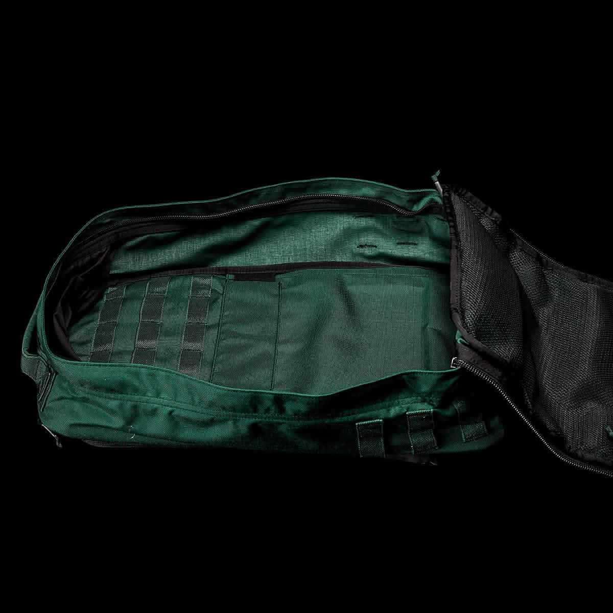 The GR1 USA - Cordura (The Original Ruck) by GORUCK, showcased in a dark green hue against a black backdrop, evokes the robust design typical of Special Forces gear, with its prominent pockets and compartments ideal for a GORUCK Challenge.