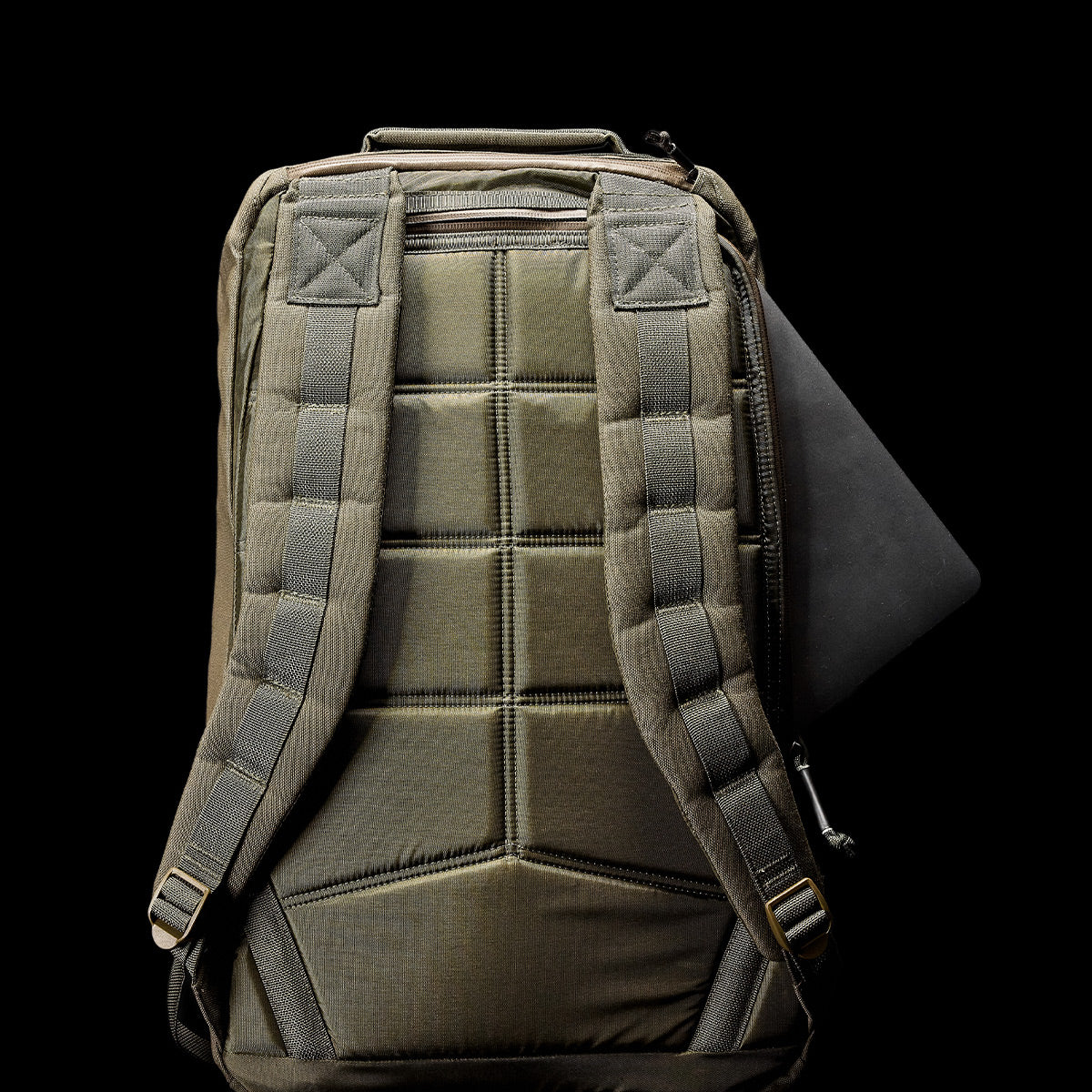 The GR1 USA - Cordura (The Original Ruck) in olive green, crafted from Special Forces-grade materials, showcases padded straps. On a black background, it’s partially open with a laptop visible.