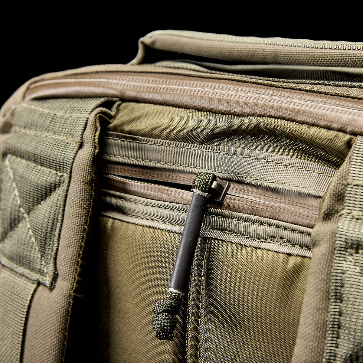 Close-up of a khaki green GR1 USA - Cordura (The Original Ruck), made with Special Forces-grade materials, highlighting zipper and strap details against a black background.