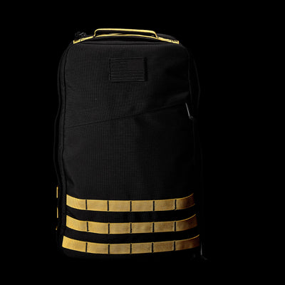 Introducing the GR1 USA - Cordura by GORUCK, this durable rucksack features yellow horizontal straps on a sleek black background. Inspired by Special Forces, it's designed to endure any challenge while maintaining its stylish appearance.