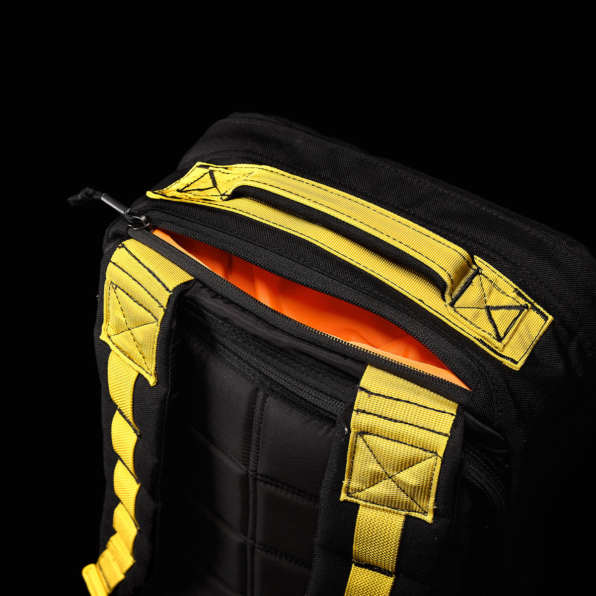 Black and yellow GR1 USA - Cordura (The Original Ruck) by GORUCK with an exposed orange interior against a black background, highlighting its robust design and the precision of American manufacturing inspired by Special Forces gear.