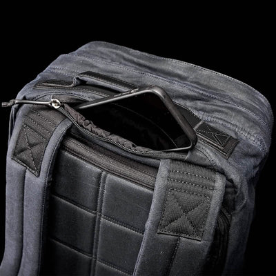 A top view of the GR2 - Waxed Canvas by GORUCK showcases its black exterior, padded straps, and an open main compartment with a smartphone partially tucked inside. The back features a textured, quilted design that exudes classic elegance.