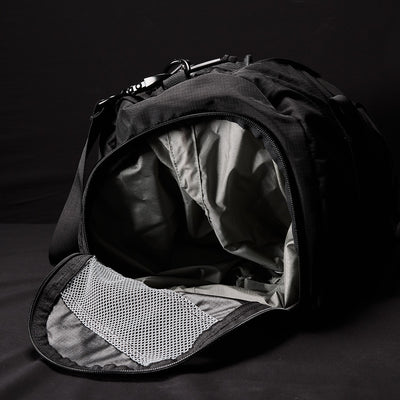 Introducing the GORUCK Gym Bag - Ripstop ROBIC®, a versatile black bag made from tough ripstop nylon, highlighted by a partially open zipper on a dark backdrop. The bag's interior lining is green, and the flap is equipped with a mesh pocket. It also includes a handy shoe compartment and features an adjustable shoulder strap for easy carrying.