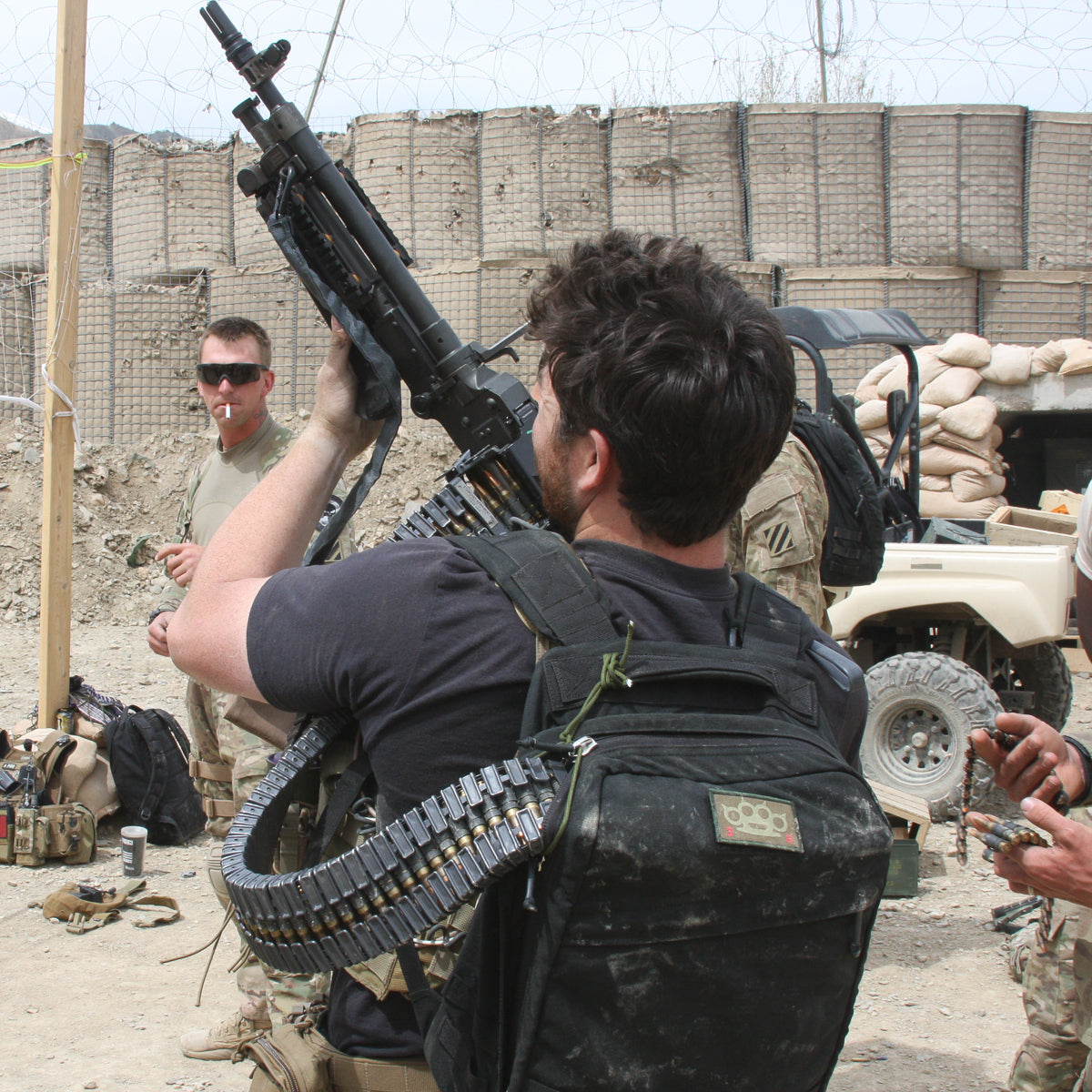 At a military base, a soldier meticulously prepares a large machine gun, embodying precision and durability akin to the GR1 USA Throwback.