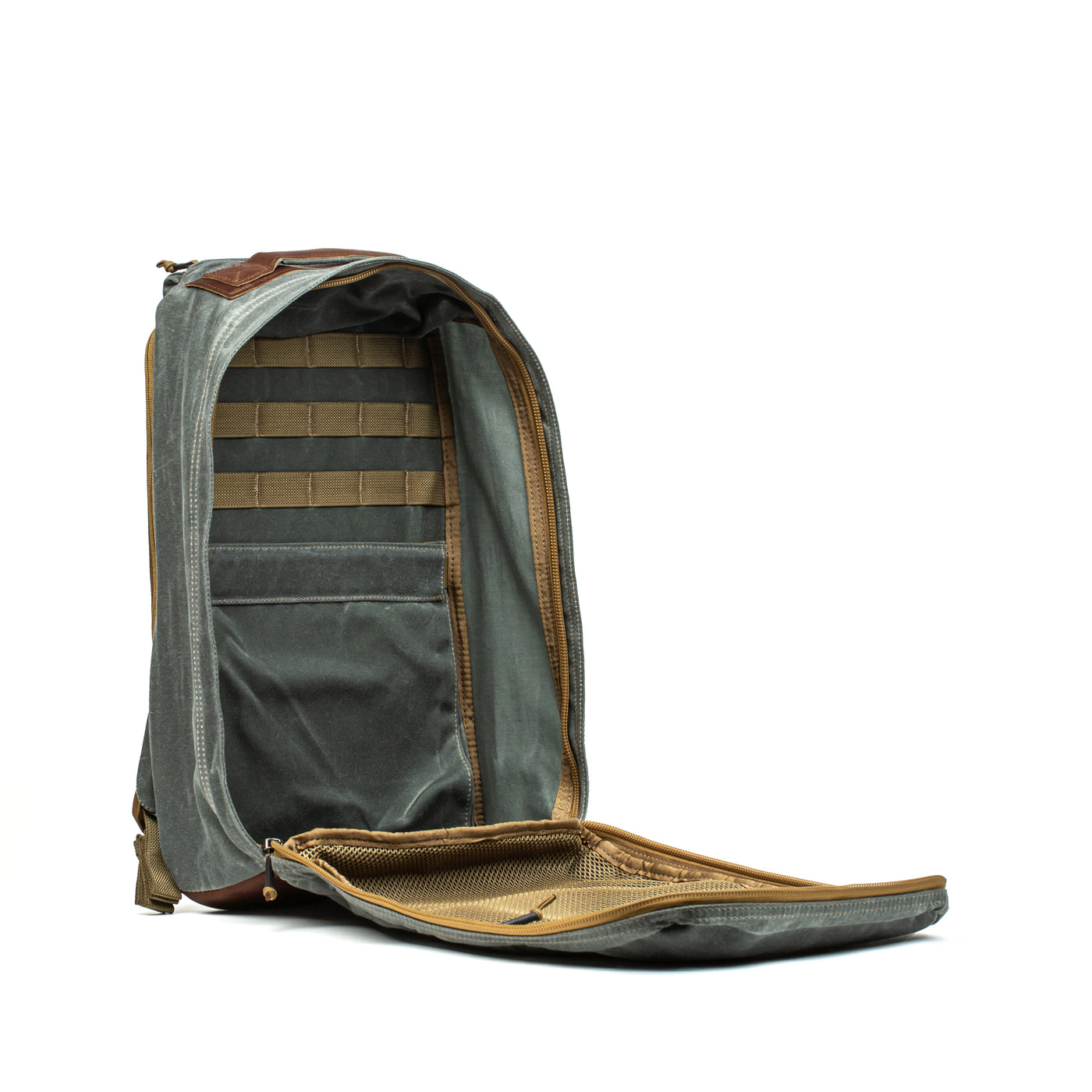 The GR1 USA - Heritage by GORUCK is a versatile open gray rucksack made from durable waxed canvas, featuring multiple compartments and pockets with mesh and padded sections to showcase its sleek functionality against a plain white background, promising both style and resilience.