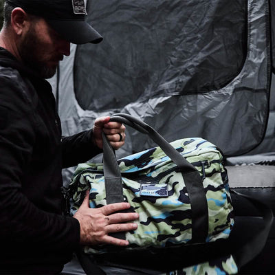 In a shadowy setting, a person clutches a Kit Bag (Includes Shoulder Strap), evoking the ruggedness of Special Forces deployment bags.