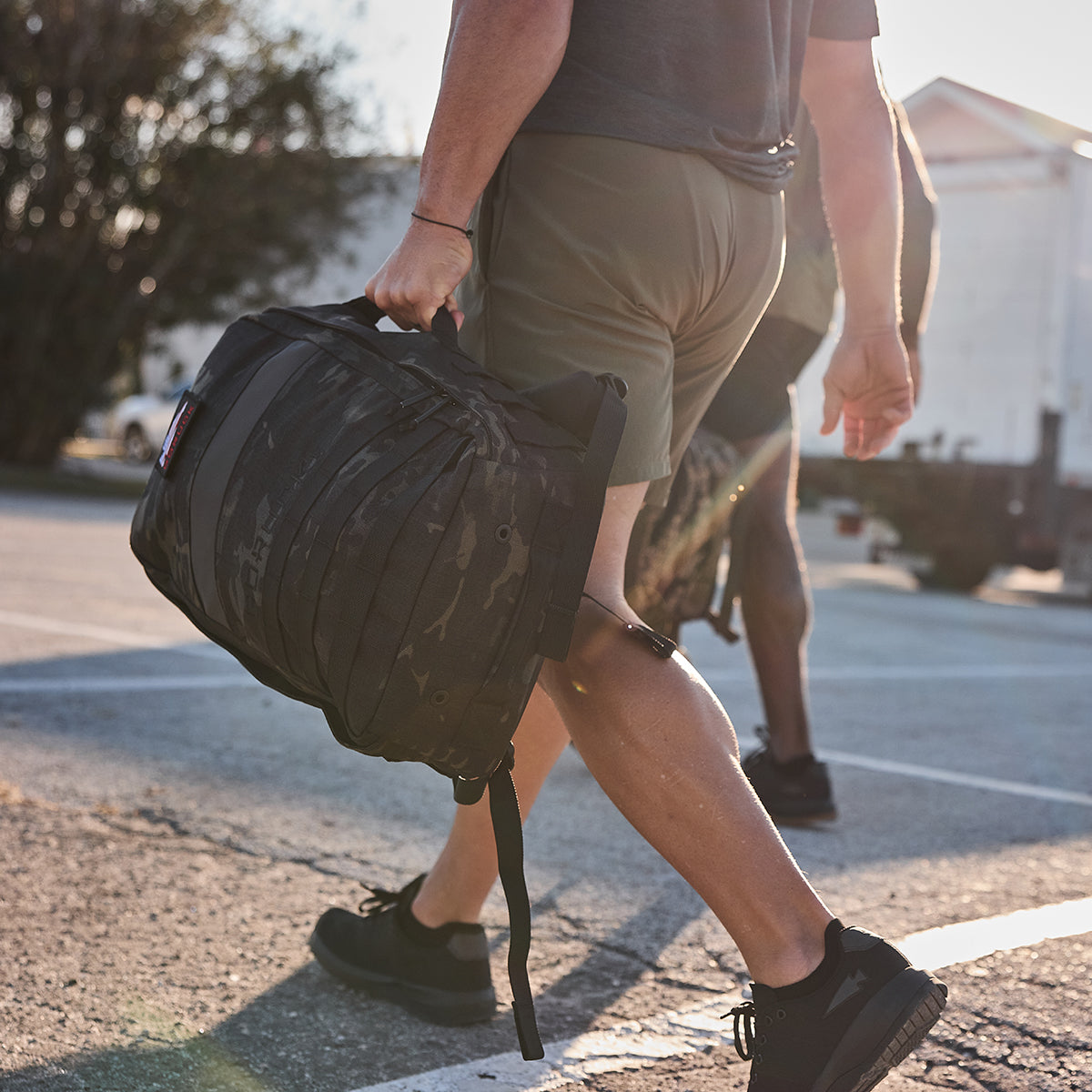 A person strolls outdoors in the sunlight, wearing shorts and a t-shirt while carrying a Rucker 4.0.