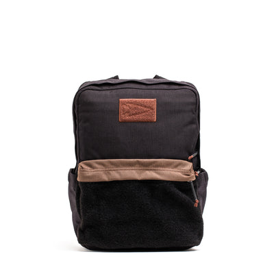 The GORUCK KR1 2.0 - Kid Ruck is a children's black backpack with brown accents, a front pocket, and reinforced stitching for enhanced durability, showcased on a white background.