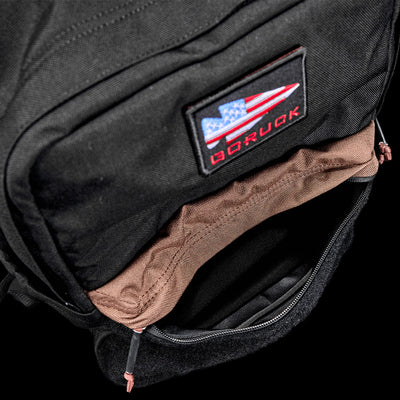 Open black KR1 2.0 - Kid Ruck backpack by GORUCK, showcasing a visible red and blue patch on the front pocket and featuring reinforced stitching for added durability.