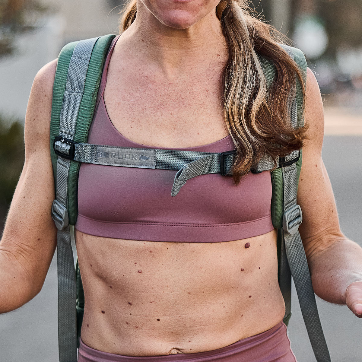 A person enjoys an outdoor walk wearing the pink Stealth Bra with ToughFlex fabric and backpack straps.